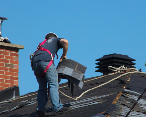 Construction Man Roofer Working On Roof Removing Shingles Repair